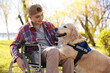 © New Africa - Teenage boy in wheelchair with his service dog at park