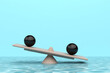 © Mingqing - seesaw with two black balls on top of it in the water