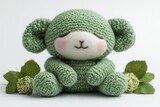 Adorable green crocheted teddy bear sitting among decorative leaves, soft background