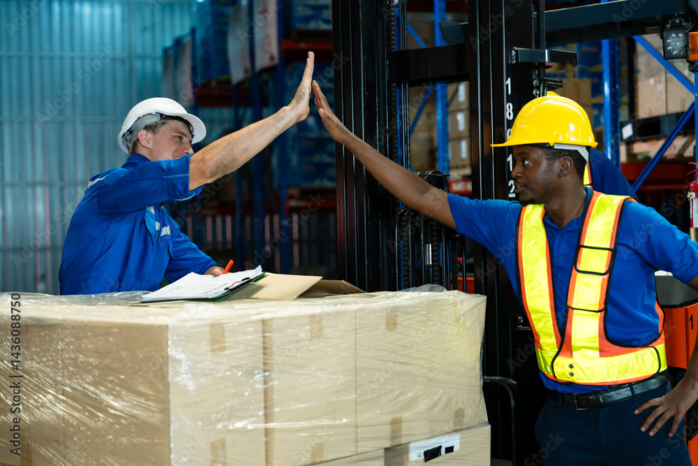 Warehouse workers wearing reflective safety vests and helmets giving ...