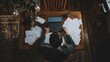 © Nazar - A remote worker sitting at a dining table, surrounded by paperwork and notes, focused on their laptop.