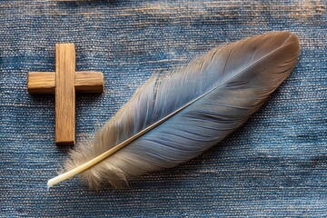 Poster - Dove feather resting gracefully beside a wooden cross on dark fabric illuminated by natural light