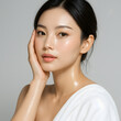 © AnilaStudio - Asian woman with glowing skin touching her face on grey background