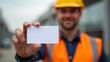 © taezhniya31 - A construction worker wearing a safety vest and helmet holds a blank card, close-up focus, blurred urban background, concept of identity or access