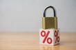 © pla2na - Padlock on percentage sign (interest rate) with white wall background. Interest rate locked in banking, financial and investment, profit locked no price increase in trading and fixed cost concept.