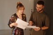 © Mediaphotos - Medium closeup of woman and director reading script notes and discussing scene details backstage during studio shoot