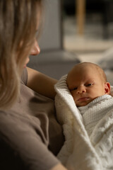 Aufkleber - Mom holds her baby wrapped in a soft blanket during a quiet moment at home in the morning light