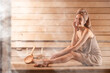 © New Africa - Smiling woman relaxing on bench surrounded by steam in sauna