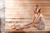 Smiling woman relaxing on bench surrounded by steam in sauna
