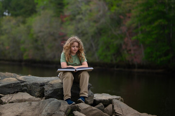 Fototapete - Kid reading book in outdoors. Child read story outdoors. Portrait of teen reading in nature. Boy with book studying on nature. Kid reading book. Child reading book in peaceful park.
