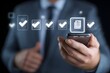 © li - Quality certificate and checklist. Businessman holding smartphone displaying digital certification and checklist icons, symbolizing online approval, compliance, and document management.