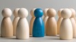 © yang - Leadership and Individuality in Business. A blue wooden figure stands apart from neutral-colored figures, symbolizing uniqueness, recruitment, diversity, and personal identity in a group setting.