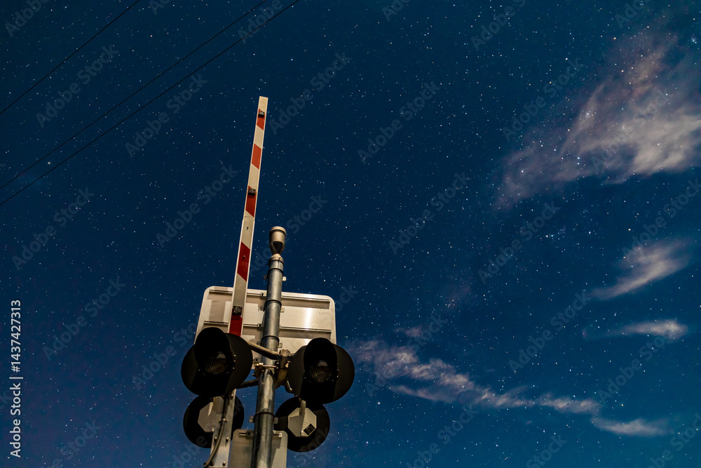 Rail crossing signals and boom barrier against the starry cloudy night ...