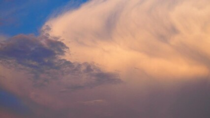 Poster - Witness the majestic beauty of a large, slowly moving cloud painted in shades of yellow, orange, pink, and blue against an enchanting sunset sky. Experience nature colorful masterpiece in motion