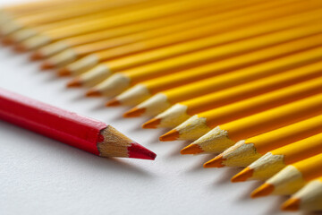 Poster - Close-up of red pencil standing out from row of yellow pencils, illustrating individuality and difference, suitable for education or uniqueness concepts