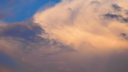 Aufkleber - Witness the majestic beauty of a large, slowly moving cloud painted in shades of yellow, orange, pink, and blue against an enchanting sunset sky. Experience nature colorful masterpiece in motion.