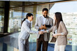 © BGStock72 - Business professionals engage in a friendly handshake on a sunny day in a modern office building