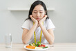 © Pormezz - unhappy asian women is on dieting time looking at broccoli on the fork. girl do not want to eat vegetables and dislike taste of broccoli.