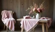 © Monster - Elegant display of pink flowers in a vase atop a table set with a fringed cloth and blanket.