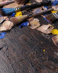 Poster - Artistic arrangement of paint brushes and paint tubes on a wooden surface ideal for creatives