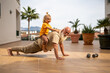© sutulastock - Grandfather doing push-ups while carrying his grandchild on his back, enjoying a fun moment of exercise together