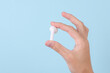 © splitov27 - Female hand holding white wireless earphone on blue background