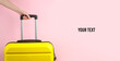 © splitov27 - Hand holding Yellow plastic travel suitcase by handle on pink background. Tourism, vacation concept. Space for your text