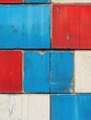 © Denis - The image features a section of an old, colorful brick wall with a red and blue pattern. The bricks are painted in various shades of red and blue, creating a lively and dynamic mosaic effect.