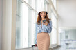 © NVB Stocker - Happy  Female Travelling use smartphone. Happy asian woman passenger traveler waiting for departure with suitcase at modern airport terminal