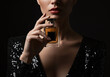 © Gita - Elegant woman in a classic black dress holding a perfume bottle with grace, highlighting mystery and charm.