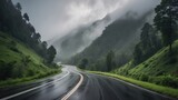 A winding, wet road meanders through a lush green landscape,