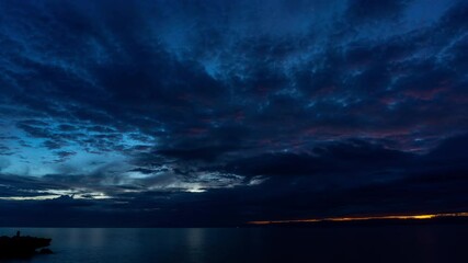 Wall Mural - dramatic clouds over tranquil sea water at sunset near a coastal location, time lapse 4k