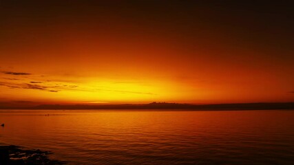 Wall Mural - stunning sunset over calm ocean waters with vibrant colors illuminating the sky, time lapse 4k