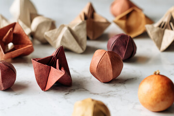 Poster - Collection of earthy-toned origami shapes scattered on marble surface, showcasing craft, texture, and design, ideal for autumnal or minimalist concepts