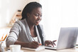 © Prostock-studio - Smiling Black Businesswoman Working On Laptop And Taking Notes In Modern Office. Free Space For Your Text