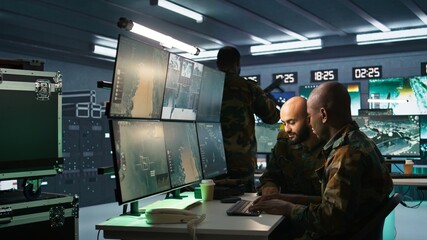 Poster - Air force officer and coworker talking while performing tactical level surveillance in command post. Teamworking military professionals using radar equipment to look at assault zones, camera B