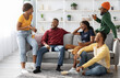 © Prostock-studio - Group Of Black Friends Enjoying Drinks Party At Home On Weekend. Cheerful african american young men and women sitting in living room, drinking beer and having conversation, home party concept