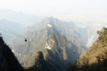 landscape high angle distant photograph of ropeway hanging on steel cable in middle of surrounding v