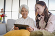 © Charlie's - Young Asian Woman Helping Grandmother For Using A Digital Tablet 