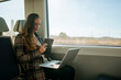 © KikoStock - Businesswoman working on laptop and taking notes on train