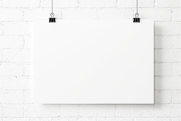 Poster - Blank white poster hanging on a white brick wall with binder clips.
