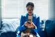 © Wasana - A woman in a blue jacket is smiling while looking at her cell phone