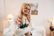 © standret - Happy facial expression. Beautiful young woman is at home with flowers