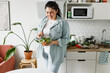 © shurkin_son - Happy plus size woman in casual clothes holding transparent bowl of delicious tasty fresh organic salad, mixing it with spoon standing at kitchen, losing weight and trying to stay healthy