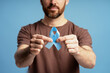 © Maria Vitkovska - Man holding light blue ribbon for prostate cancer awareness
