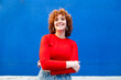 © VISTA by Westend61 - Confident woman with curly hair smiling against a blue background
