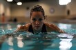 © Yuliya - Focused Swimmer in Pool: A determined female swimmer executes a graceful butterfly stroke in a serene indoor pool, embodying athletic prowess and the embodiment of intense focus and dedication.
