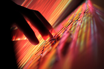 Aufkleber - Silhouette of hand interacting with illuminated keyboard, red and orange light streaks create dynamic background, suggesting digital activity or technological interaction