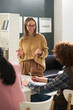 © Mediaphotos - Teacher smiling and interacting with students in classroom, holding paper while students take notes, creating interactive and productive learning environment, fostering engagement and understanding