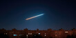 © SnowElf - Streak of light streaking across clear night sky above row of illuminated apartment buildings, creating a contrast between urban setting and celestial phenomenon, invoking a sense of wonder